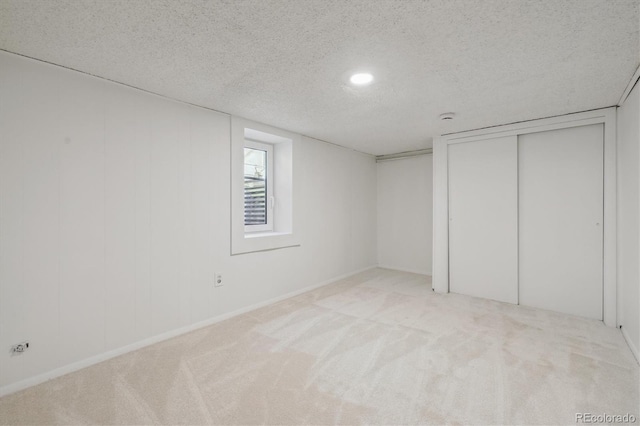 basement with carpet floors, a textured ceiling, and baseboards