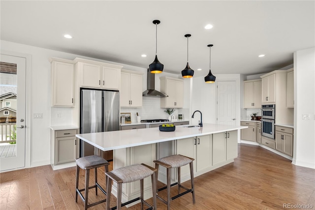 9566 Poppy Way, Arvada, CO 80007 - kitchen with wall chimney range hood, appliances with stainless steel finishes, backsplash, light wood-style flooring, and recessed lighting