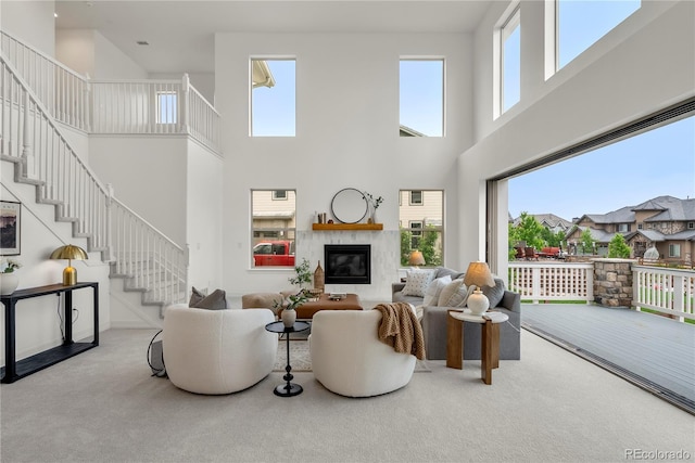 9566 Poppy Way, Arvada, CO 80007 - living room with a towering ceiling, carpet floors, stairs, healthy amount of natural light, and a glass covered fireplace