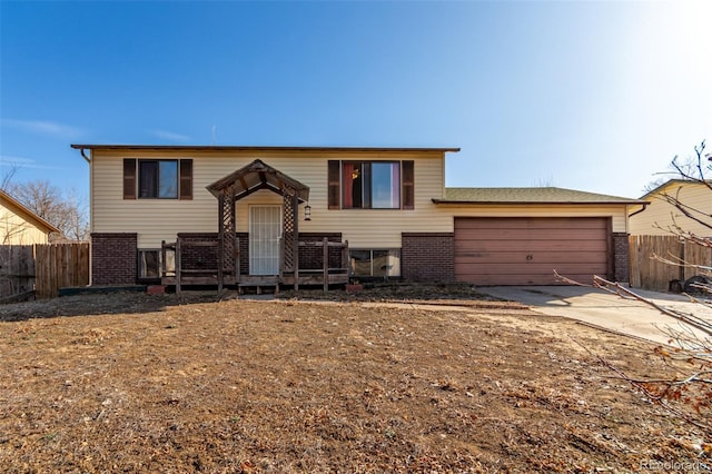 raised ranch with brick siding, fence, concrete driveway, cooling unit, and a garage