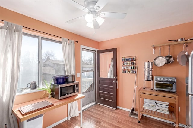 interior space featuring baseboards, light wood-style floors, and ceiling fan