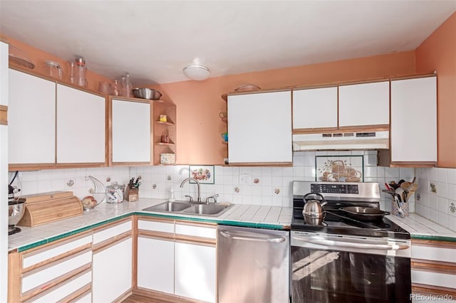 kitchen featuring under cabinet range hood, a sink, tasteful backsplash, white cabinetry, and stainless steel appliances