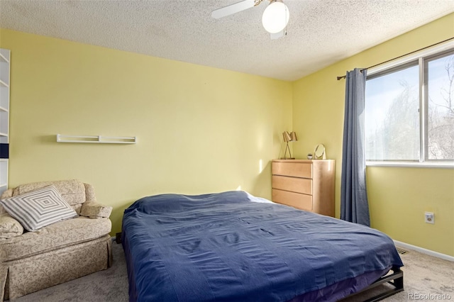 carpeted bedroom featuring ceiling fan, baseboards, and a textured ceiling