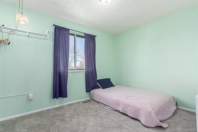 bedroom featuring visible vents, carpet floors, a textured ceiling, and baseboards