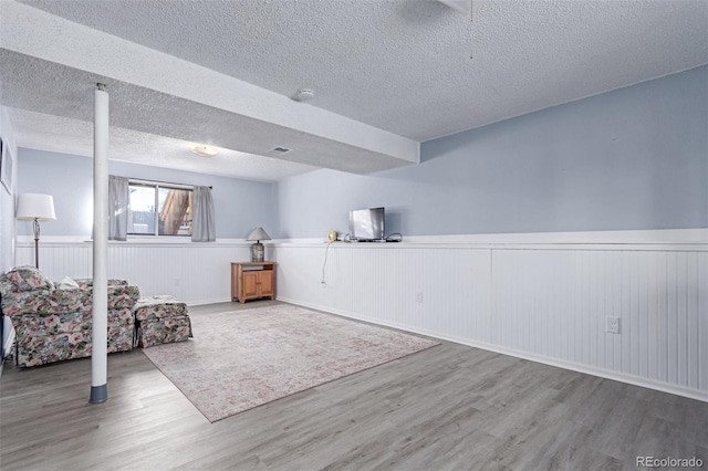 interior space featuring a wainscoted wall, a textured ceiling, and wood finished floors