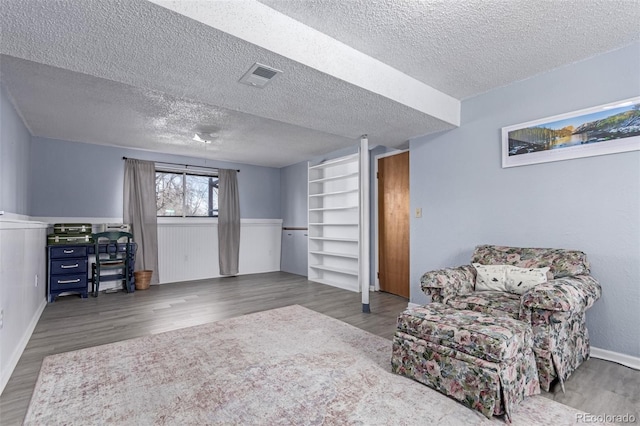 living area featuring visible vents, a textured ceiling, and wood finished floors