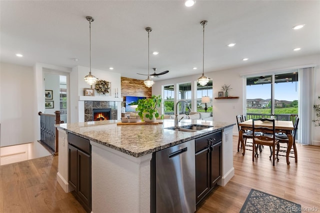 11817 Phoebe St, Parker, CO 80134 - kitchen with stainless steel dishwasher, open floor plan, light wood-type flooring, light stone counters, and ceiling fan