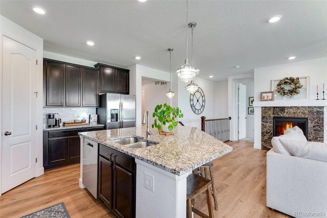 11817 Phoebe St, Parker, CO 80134 - kitchen with appliances with stainless steel finishes, open floor plan, light stone countertops, a kitchen bar, and dark brown cabinets