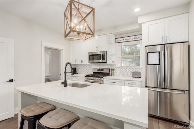 5123 W 41st Ave, Denver, CO 80212 - kitchen with stainless steel appliances, backsplash, a center island with sink, white cabinetry, and dark wood finished floors