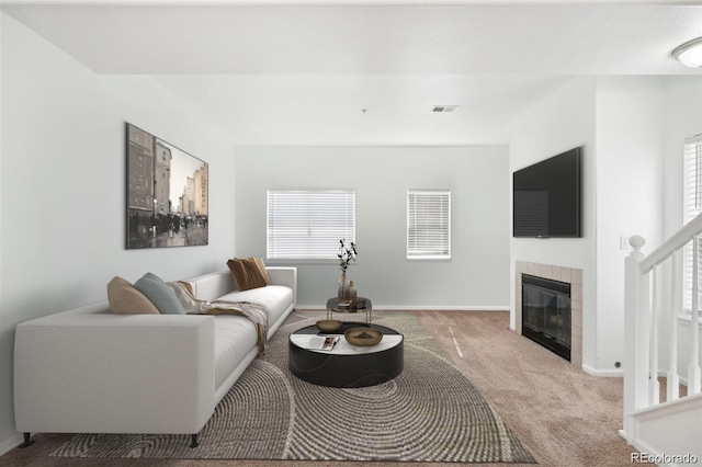 carpeted living room with baseboards, visible vents, and a tiled fireplace