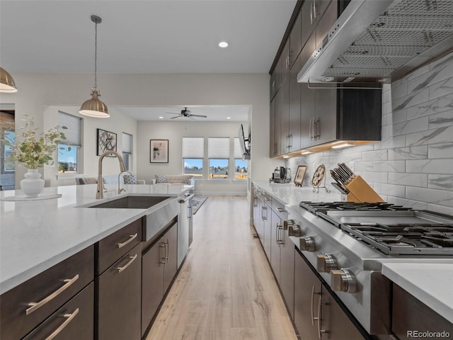 kitchen featuring decorative backsplash, ventilation hood, sink, stovetop, and hanging light fixtures