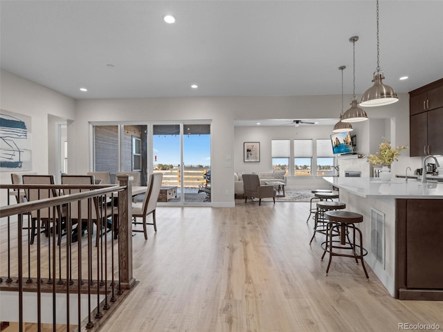 dining room with ceiling fan, sink, and light hardwood / wood-style flooring