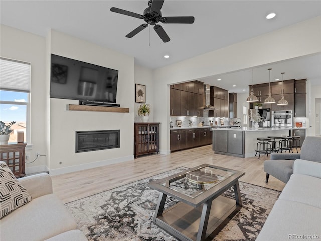 living room with ceiling fan, light hardwood / wood-style flooring, and sink