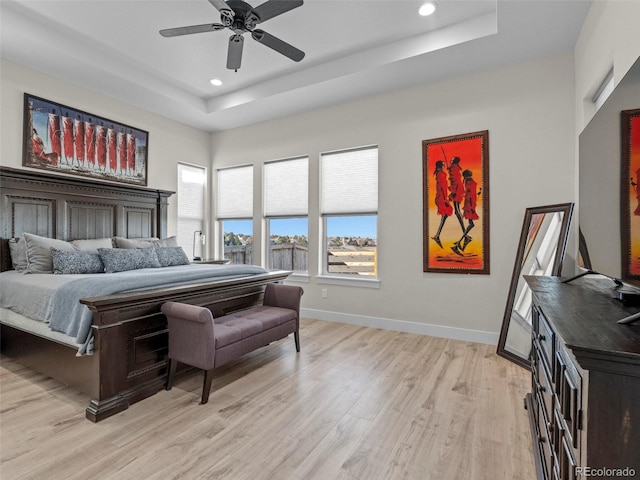 bedroom featuring a tray ceiling, ceiling fan, and light hardwood / wood-style floors