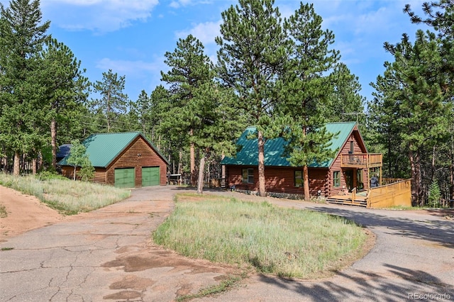 log cabin with a deck, a garage, and an outbuilding