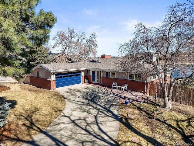 ranch-style home featuring fence, driveway, an attached garage, a chimney, and brick siding