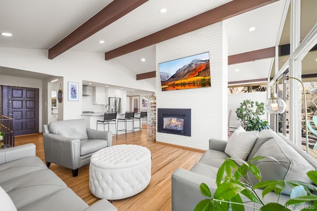 living area with recessed lighting, a brick fireplace, vaulted ceiling with beams, and light wood finished floors