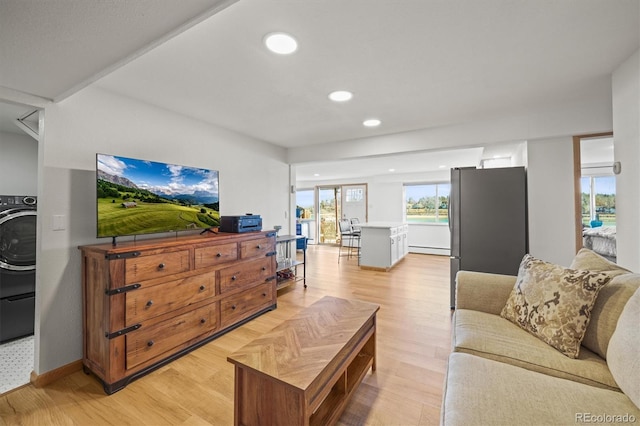 living room featuring light wood finished floors, baseboards, baseboard heating, recessed lighting, and washer / dryer