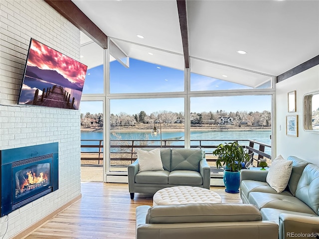 living room with a fireplace, lofted ceiling with beams, floor to ceiling windows, and wood finished floors