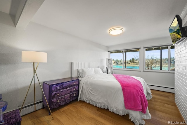 bedroom featuring a baseboard heating unit, baseboard heating, and wood finished floors