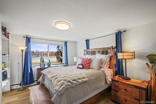 bedroom with baseboard heating and wood finished floors