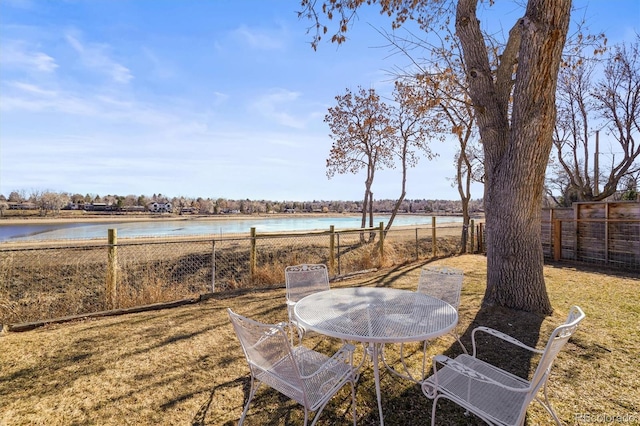 view of yard featuring outdoor dining area, a water view, and fence