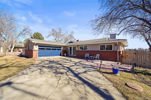 view of front of home with brick siding, an attached garage, concrete driveway, and fence