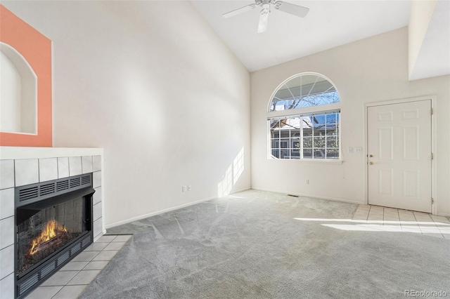 unfurnished living room featuring light carpet, high vaulted ceiling, a tile fireplace, and ceiling fan