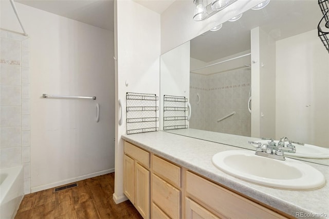 bathroom with hardwood / wood-style flooring, vanity, and washtub / shower combination