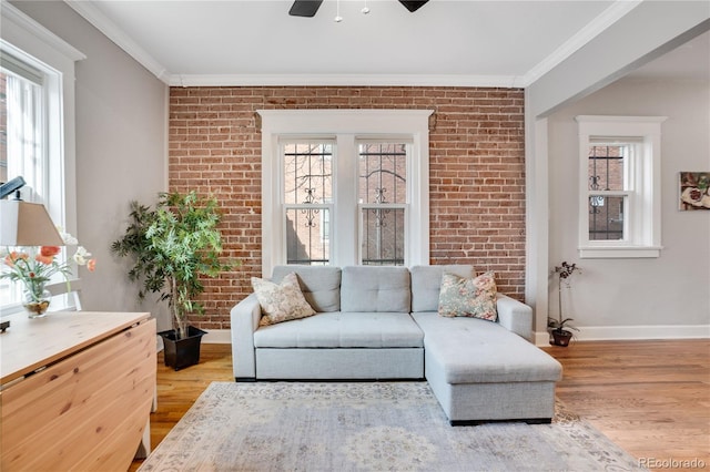 living room featuring crown molding, brick wall, and light hardwood / wood-style floors