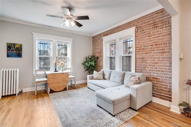 living room featuring radiator, ceiling fan, brick wall, and ornamental molding