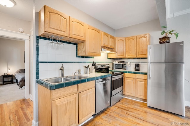 kitchen with tile countertops, light hardwood / wood-style floors, sink, and stainless steel appliances