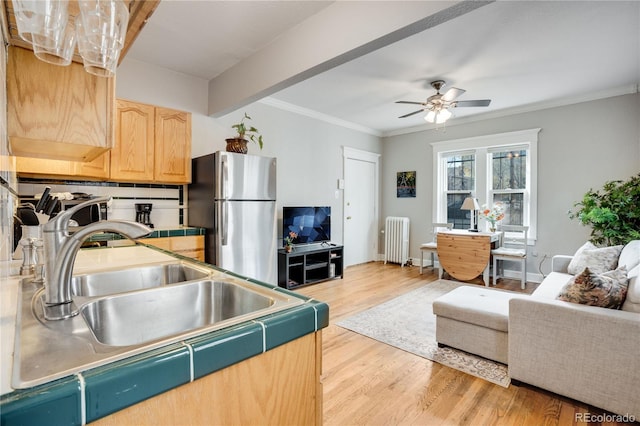 kitchen featuring radiator, sink, light brown cabinets, stainless steel fridge, and light wood-type flooring