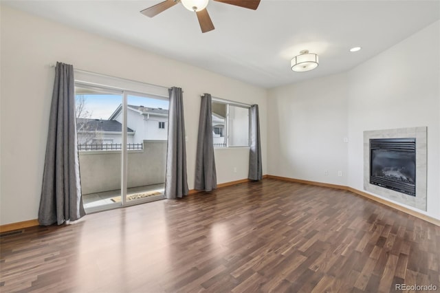 unfurnished living room with ceiling fan, dark hardwood / wood-style flooring, and a tile fireplace