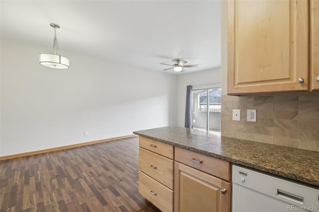 kitchen featuring backsplash, white dishwasher, dark stone counters, decorative light fixtures, and light brown cabinetry