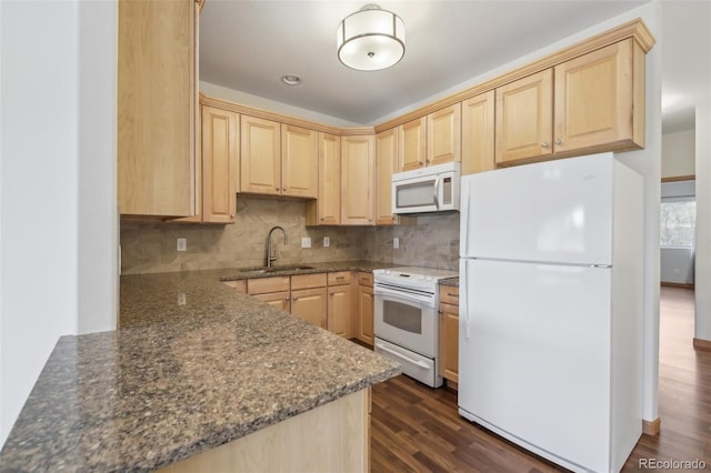 kitchen with dark stone countertops, sink, light brown cabinetry, and white appliances