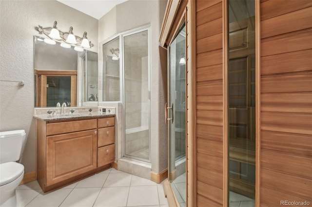 bathroom featuring tile patterned floors, vanity, toilet, and a shower with door