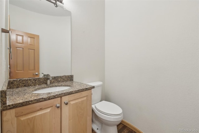 bathroom with wood-type flooring, vanity, and toilet