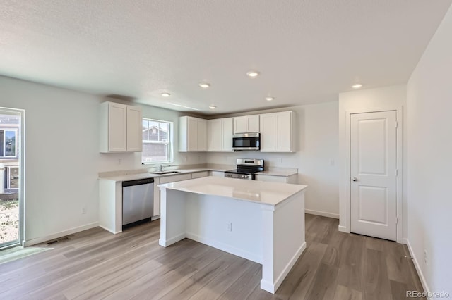 22094 E 39th Pl, Aurora, CO 80019 - kitchen with stainless steel appliances, light wood-style floors, white cabinets, light countertops, and recessed lighting