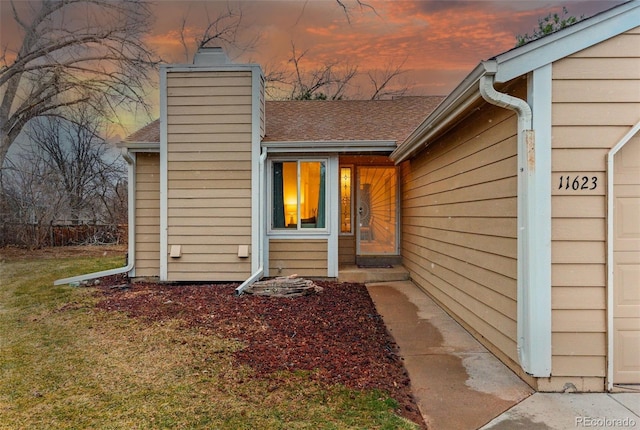 exterior space with roof with shingles and a chimney