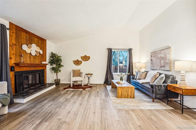 living area featuring a large fireplace, baseboards, wood finished floors, vaulted ceiling, and a textured ceiling