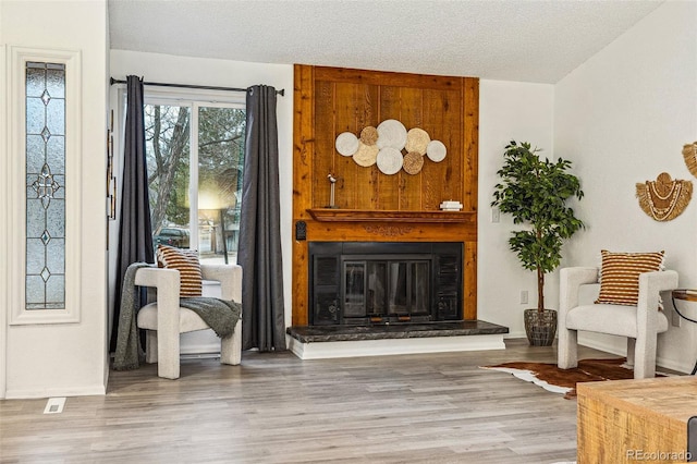 sitting room featuring a textured ceiling, a fireplace, and wood finished floors