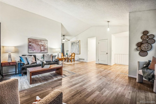 living area featuring high vaulted ceiling, a textured ceiling, baseboards, and wood finished floors