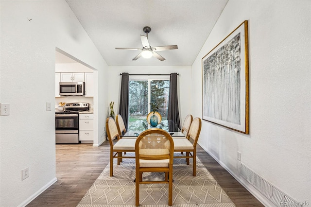 dining room with light wood-type flooring, ceiling fan, lofted ceiling, and baseboards