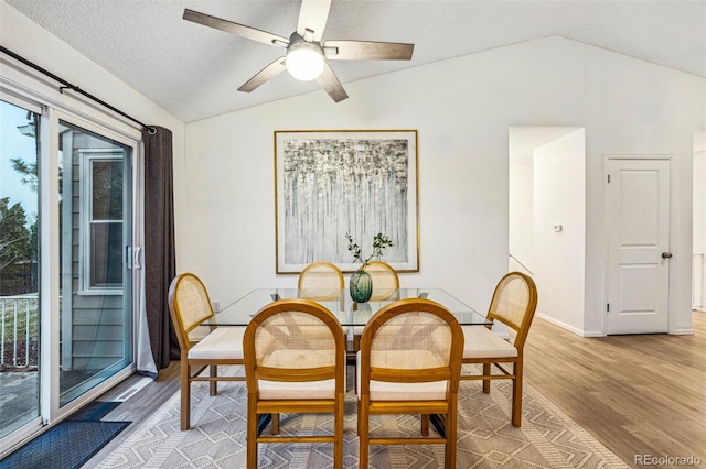 dining room featuring vaulted ceiling, light wood finished floors, a textured ceiling, and a ceiling fan