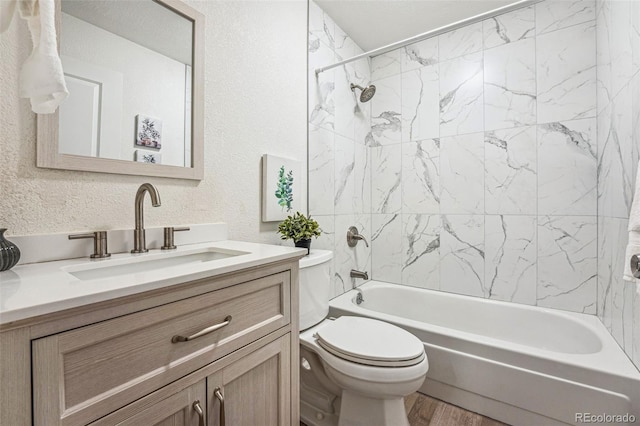 bathroom featuring bathing tub / shower combination, toilet, a textured wall, wood finished floors, and vanity