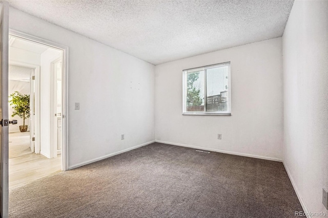 carpeted empty room featuring a textured ceiling and baseboards