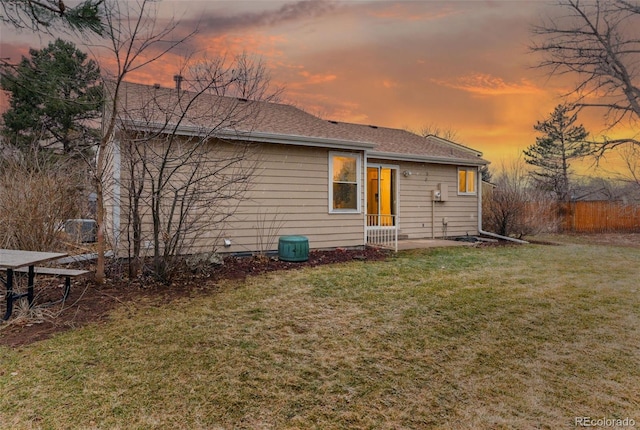 back of house featuring a shingled roof, a patio, and a yard