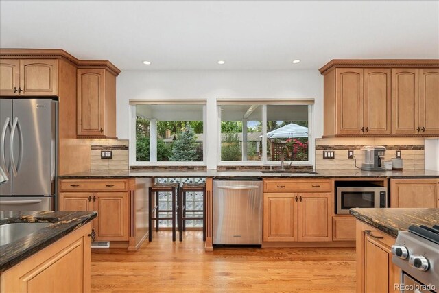 3765 E Easter Dr, Centennial, CO 80122 - kitchen featuring appliances with stainless steel finishes, dark stone counters, plenty of natural light, backsplash, and recessed lighting