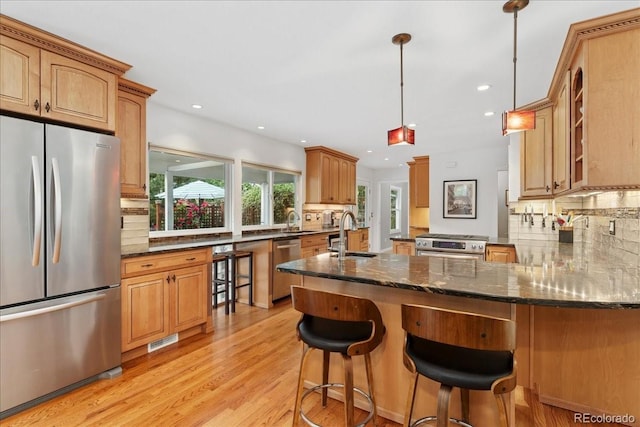 3765 E Easter Dr, Centennial, CO 80122 - kitchen featuring stainless steel appliances, light wood finished floors, a peninsula, dark stone counters, and a breakfast bar